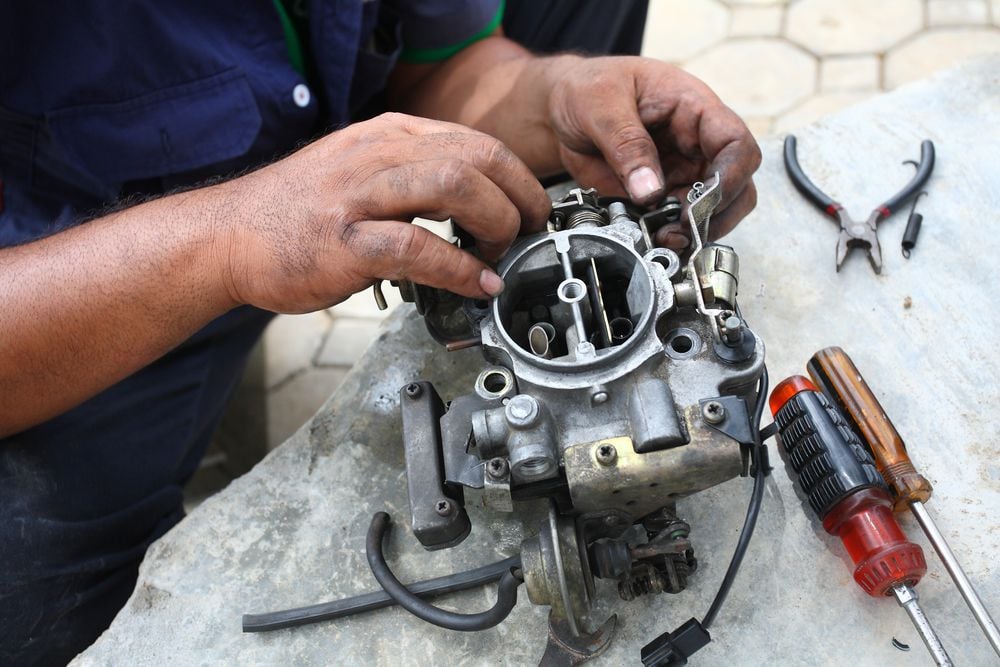 A mechanic rebuilding a faulty carburetor.