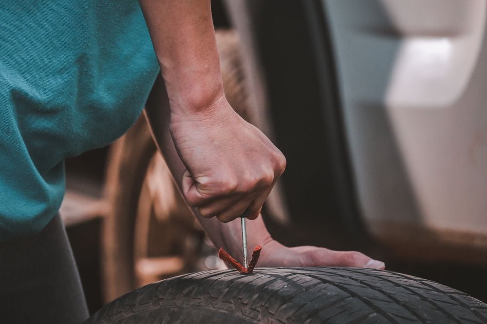 Mechanic repairing a flat tire with a puncture repair kit