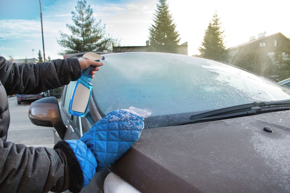 Spraying an alcohol spray on a frosted windshield